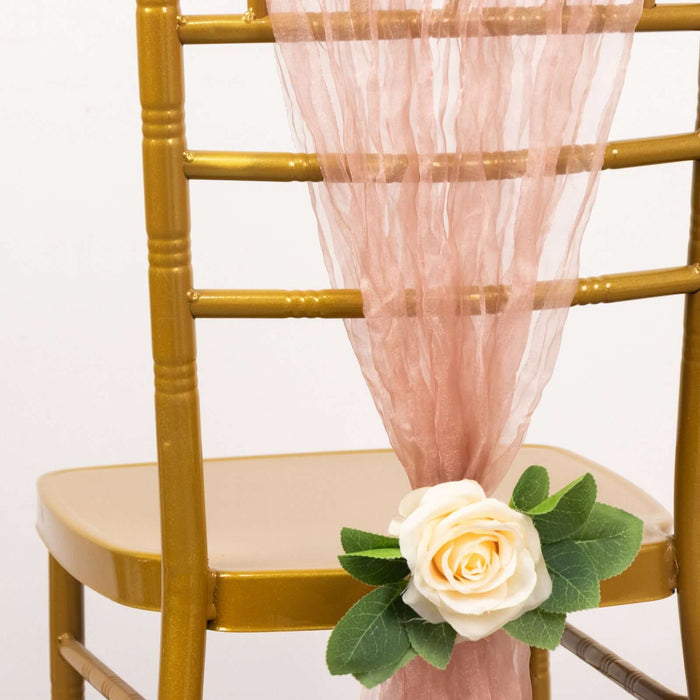 Gold chiavari chair with pink sheer fabric and a white rose decoration.