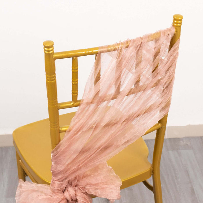 Gold chiavari chair with pink draped fabric on the back.