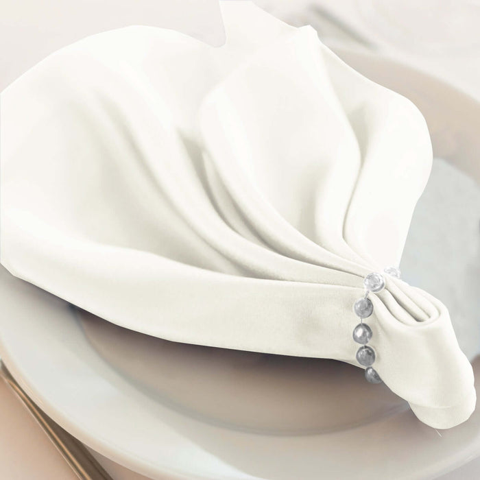 Elegant white napkin elegantly folded on a plate with decorative beads.