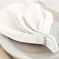 Elegant white napkin elegantly folded on a plate with decorative beads.