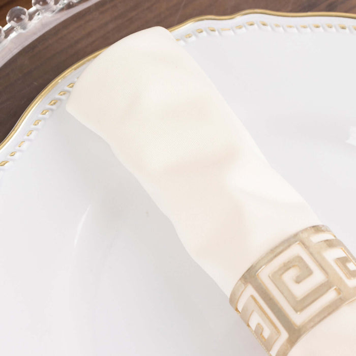 Elegant white napkin with gold Greek key design on fine china plate.