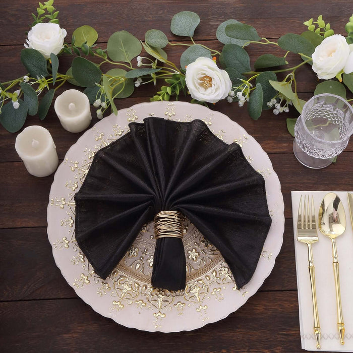 Elegant black napkin with gold ring on a decorated dinner plate and floral accents.