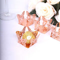 Rose gold butterfly candy wrappers on a table with white roses.