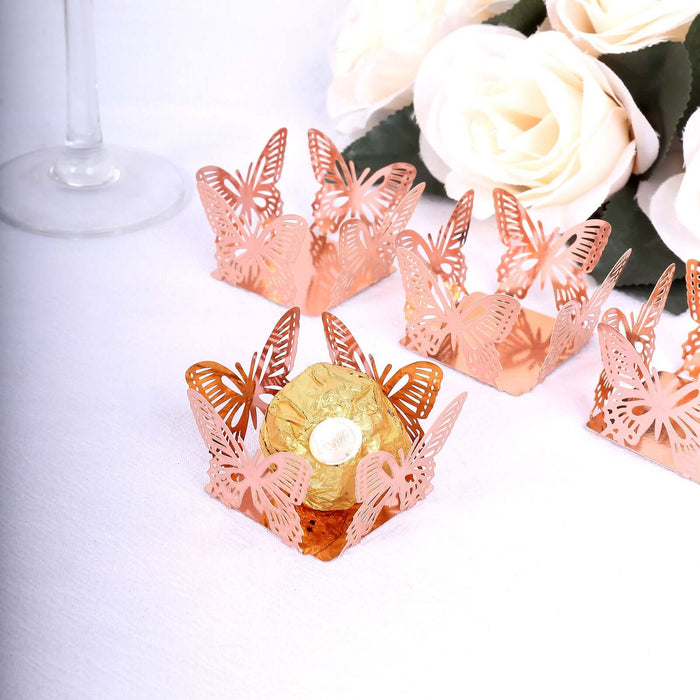 Rose gold butterfly candy wrappers on a table with white roses.