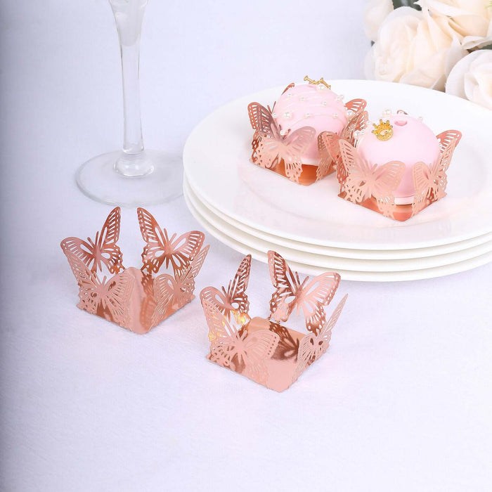 Rose gold butterfly cupcake wrappers on a white table with decorated cupcakes.