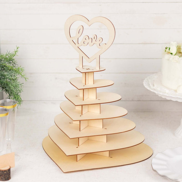 Wooden heart-shaped cupcake stand with "love" topper in studio setting.