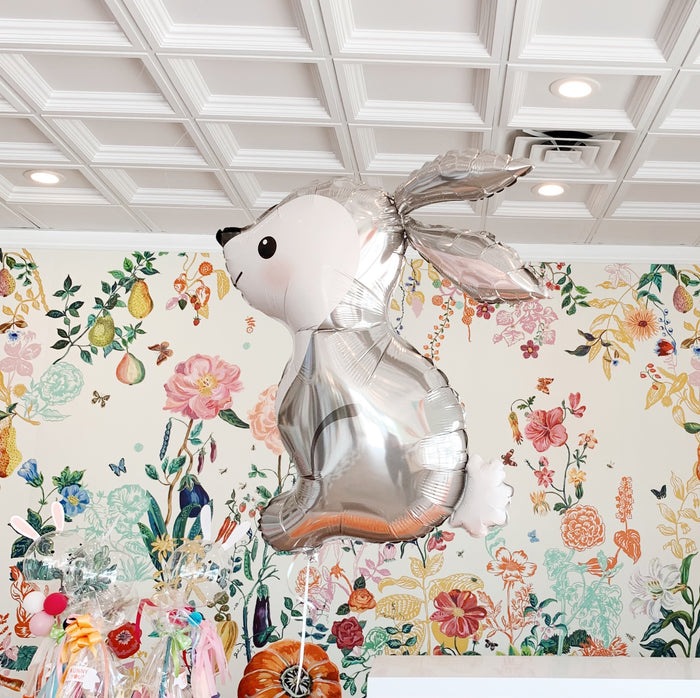 grey bunny inside a cafe with floral wall