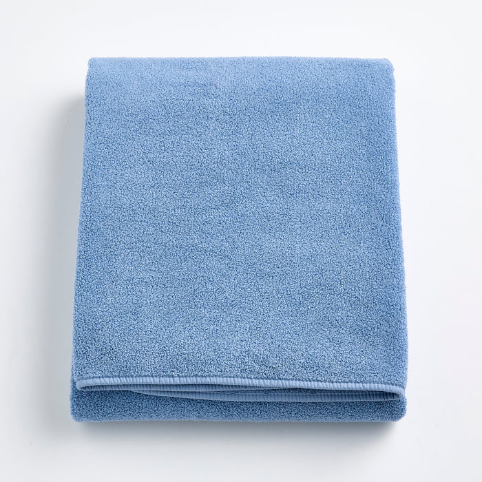 Folded denim blue Signature bath sheet in plush, absorbent cotton terry fabric with a clean hemmed edge.