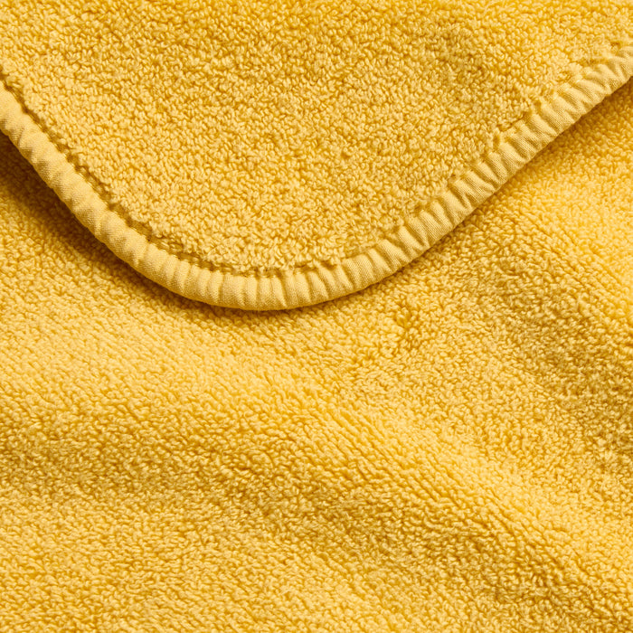 Bright yellow Signature washcloth made of soft, absorbent cotton terry fabric with a stitched hemmed edge.