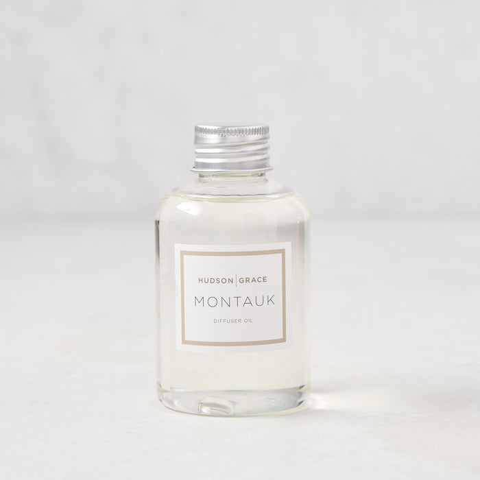 Hudson Grace Montauk scented reed diffuser oil refill, clear glass bottle with silver cap and white label.