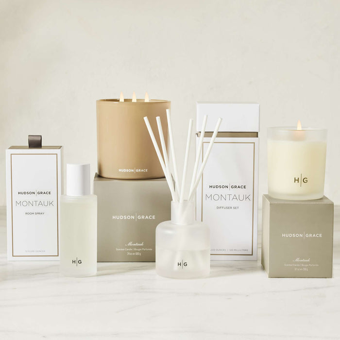 Hudson Grace Montauk scented reed diffuser oil refill bottle, room spray, and candles in white and beige packaging.