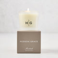 Hudson Grace Montauk Scented Votive candle in a frosted glass vessel with "HG" logo, on a taupe gift box.