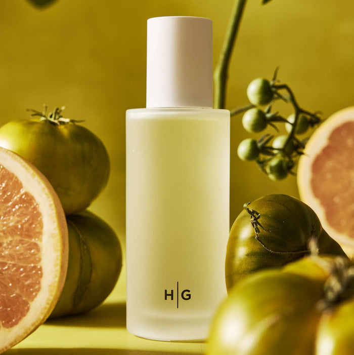 Hudson Grace San Marzano Votive, frosted glass bottle with HG logo, surrounded by green tomatoes and grapefruit.