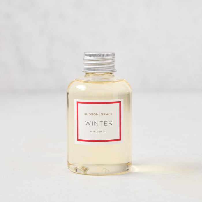 Hudson Grace Winter Scented Reed Diffuser oil bottle, clear glass with silver cap and white label.