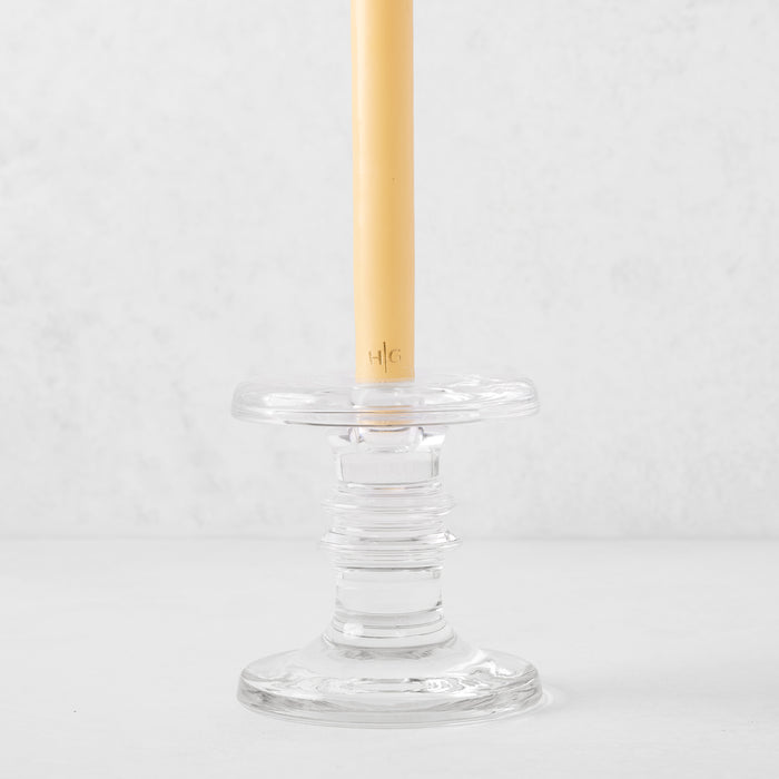 Medium clear glass taper candleholder with ridges, holding a beige taper candle.