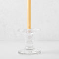 Medium clear glass taper candleholder with ridges, holding a beige taper candle.