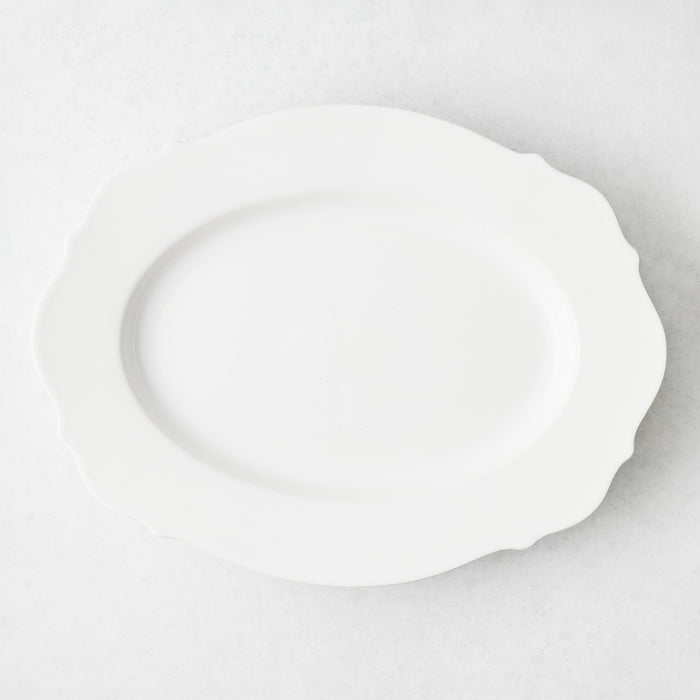 Large oval white ceramic serve platter with softened scalloped edges, made in Italy.