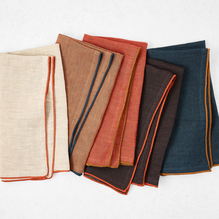 Set of 22-inch square linen napkins in assorted colors with contrasting embroidered tipped edges.