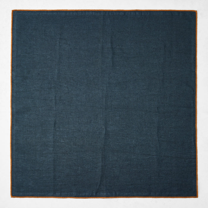 22-inch square navy blue linen napkin with a contrasting camel brown embroidered tipped stitch edge.