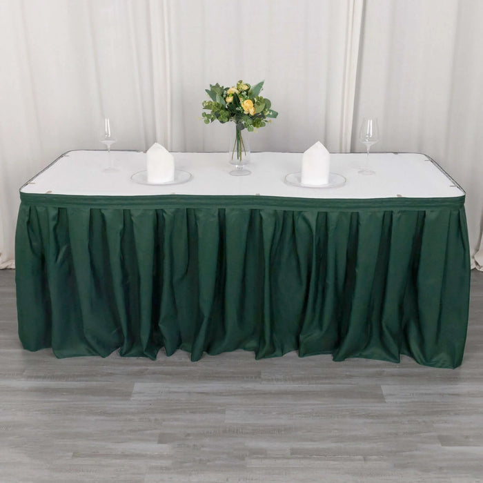 Green table skirt draped over a table set with plates and a vase of flowers.