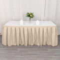 Beige tablecloth draped over a long table with floral centerpiece and plates.