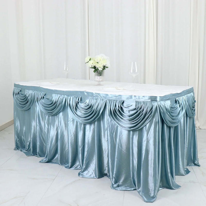 Elegant blue satin table skirt draped with decorative pleats and floral centerpiece.