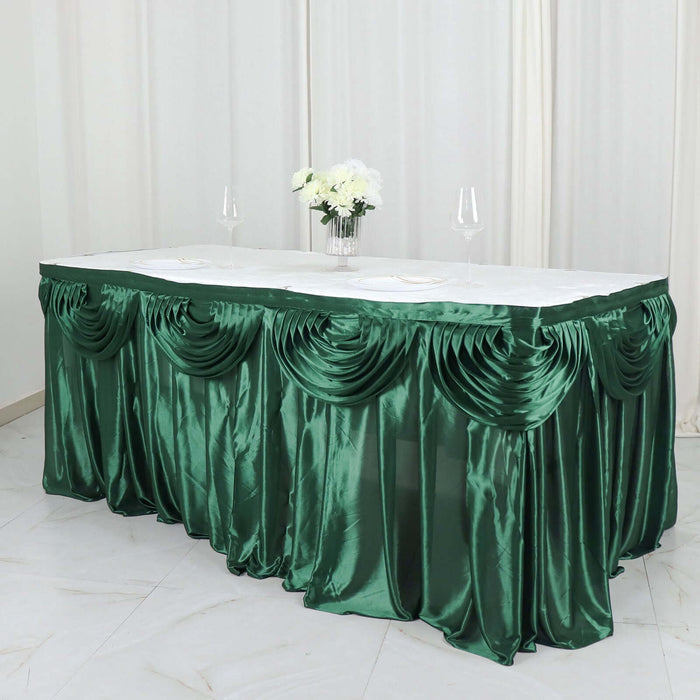 Green satin table skirt with elegant draping for events and decorations.