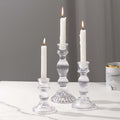 Elegant clear glass candle holders with white candles lit.