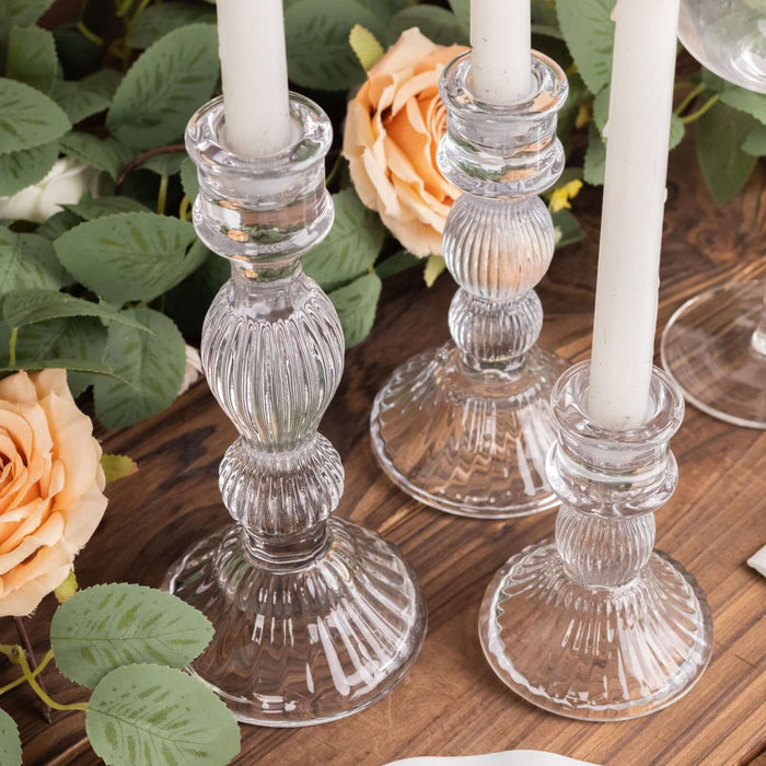Elegant glass candle holders with white candles and floral accents.