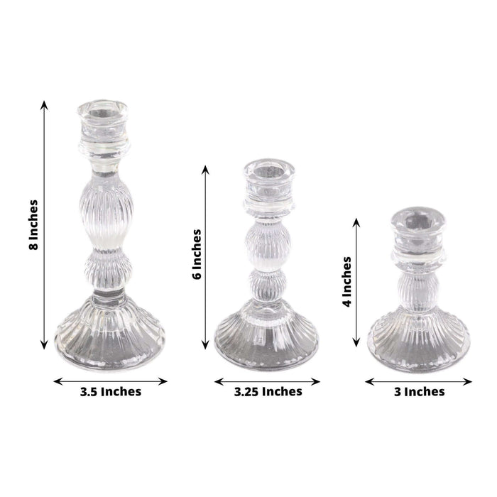 Set of three clear glass candlesticks in varying heights.