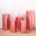 Set of five pink metallic pedestals in various heights on a light background.