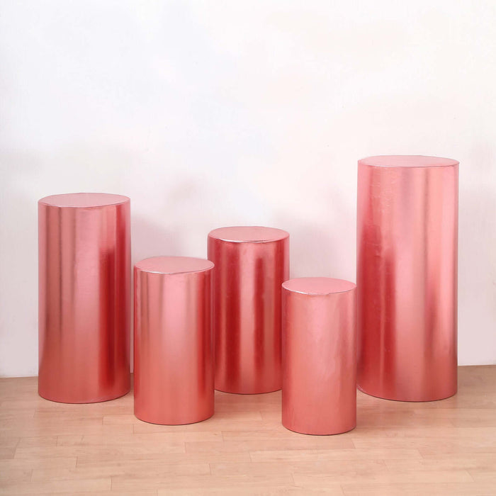 Set of five shiny rose gold pedestals in varying heights and sizes.