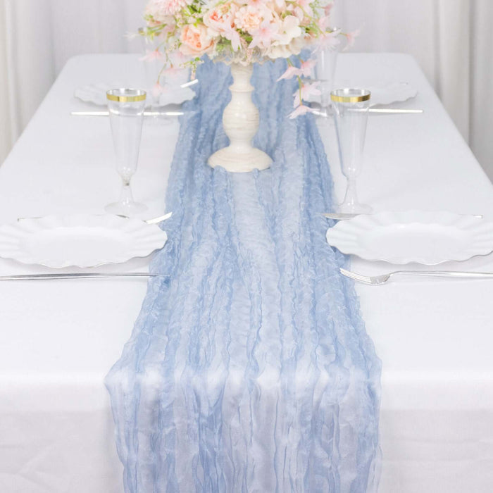 Light blue table runner on a white table set with elegant dinnerware and floral centerpiece.