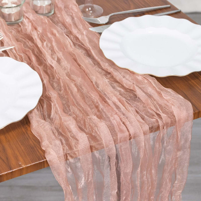 Textured pink table runner on a wooden table with white plates and glassware.