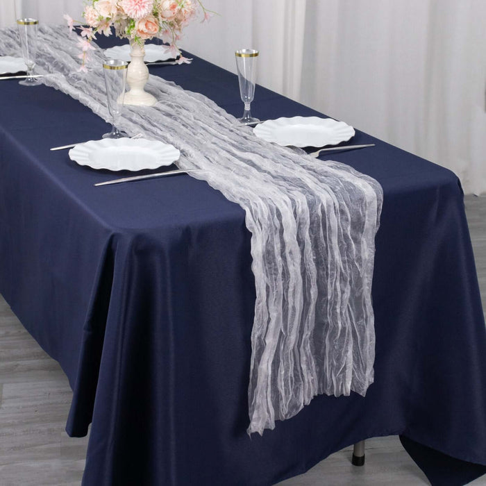 Elegant gray table runner on a navy table setting with plates and glasses.