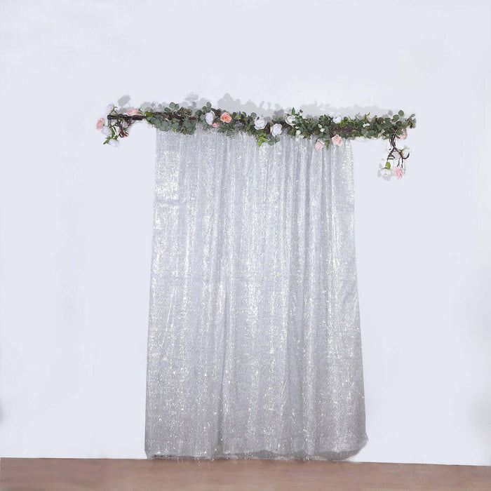 Silver sequin curtain with floral garland on top against a white backdrop