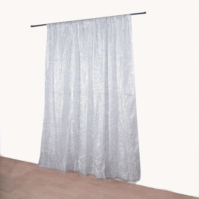 Silver sheer curtain hanging on a rod against a plain wall.