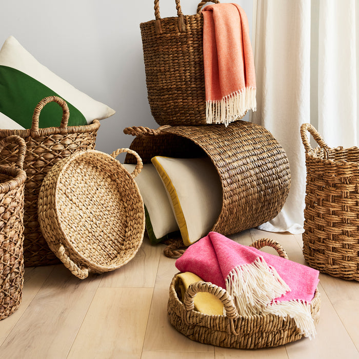 Woven hyacinth leaf baskets in various sizes, some holding blankets and pillows.