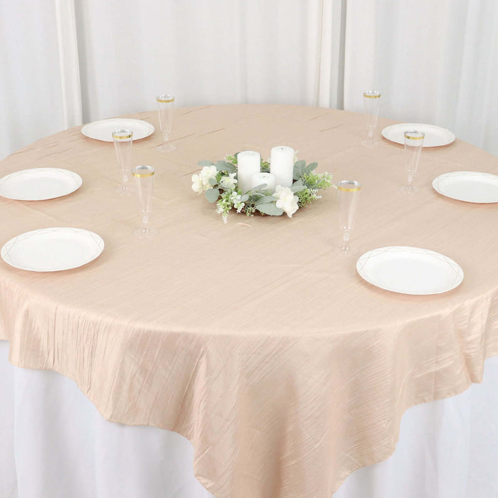 Elegant round table set with plates and candles on a soft beige tablecloth.