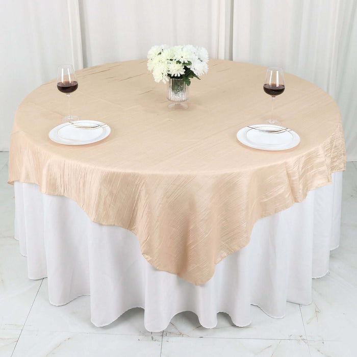 Elegant round table set with beige tablecloth, white plates, and wine glasses.