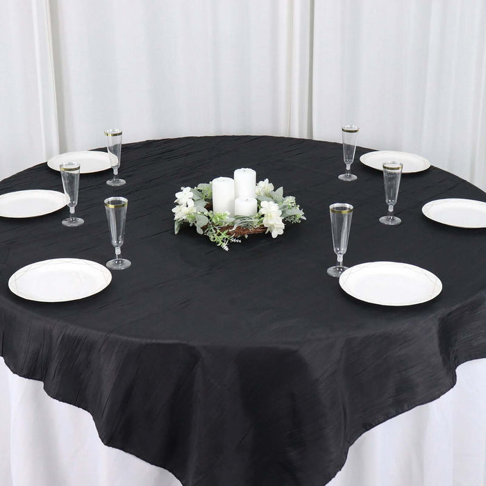 Elegant black tablecloth set for dining with candles and floral centerpiece.