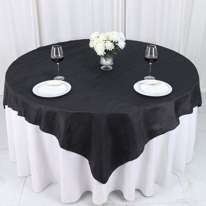 Round black tablecloth draped over a white table with wine glasses and plates.