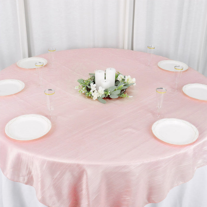 Pink tablecloth with plates and floral centerpiece on a round table.