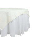 Round white tablecloth with a textured design on a plain background.