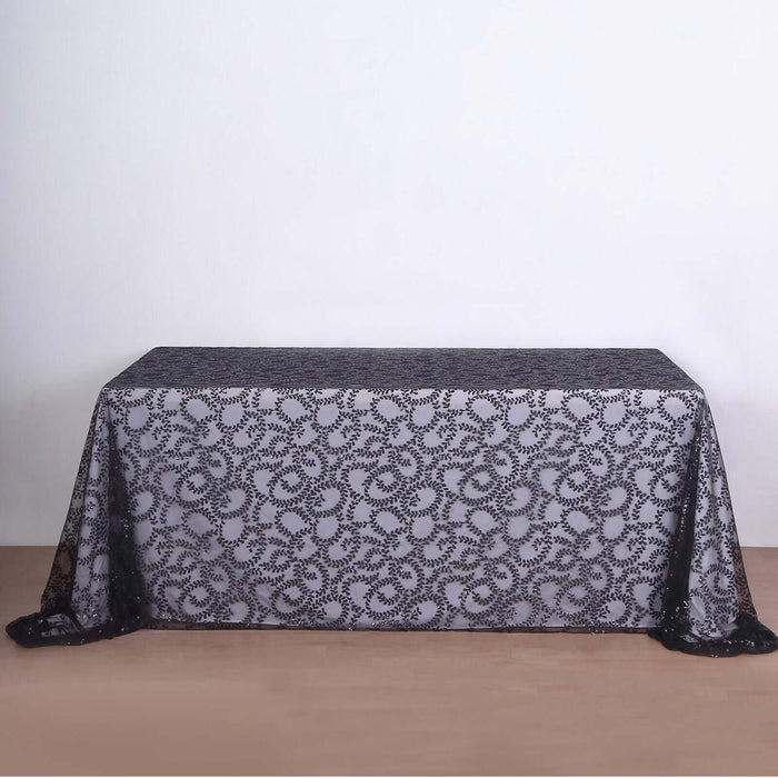 Black lace tablecloth with intricate floral design on a plain backdrop.