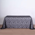 Black lace tablecloth with intricate floral design on a plain backdrop.