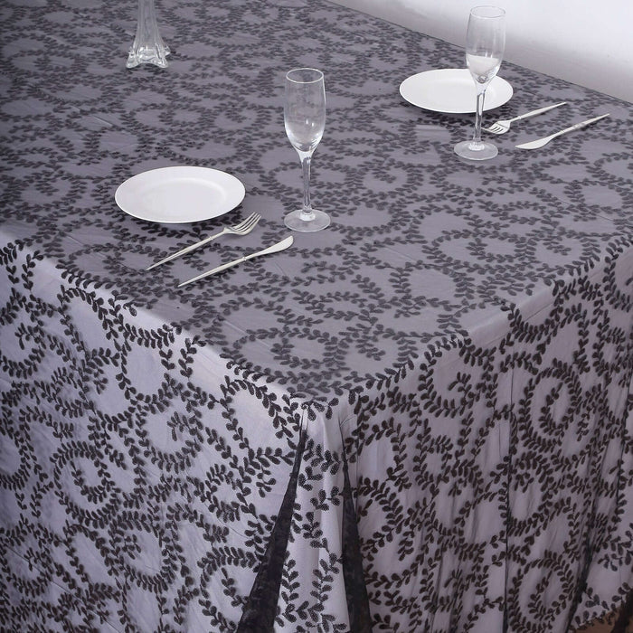 Elegant gray patterned tablecloth set for dining with plates and cutlery.