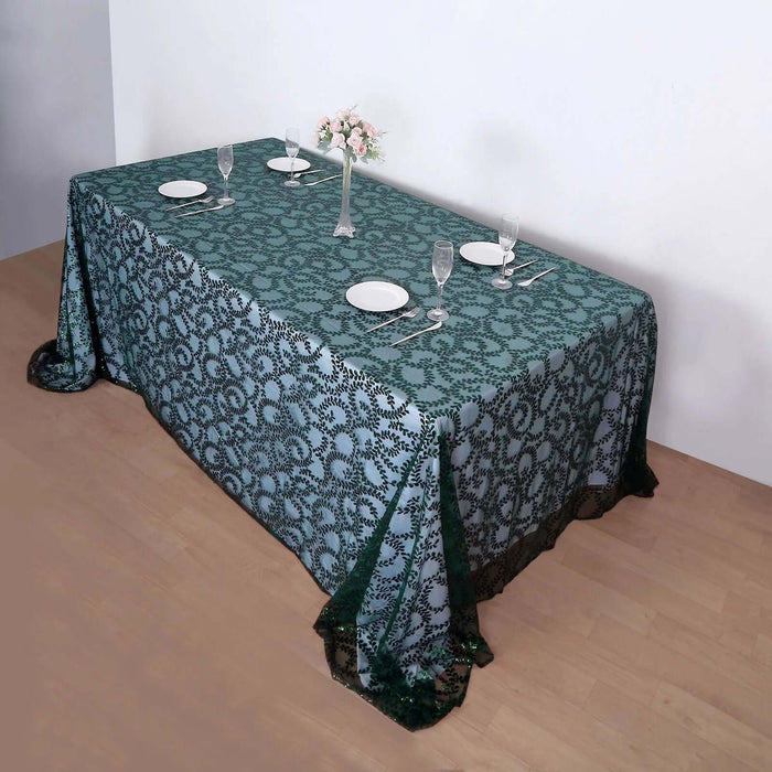 Elegant green lace tablecloth on a dining table with plates and glasses.