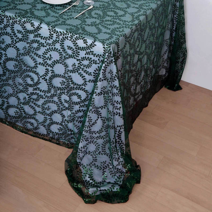 Elegant green tablecloth with intricate leaf design draped on a wooden table.
