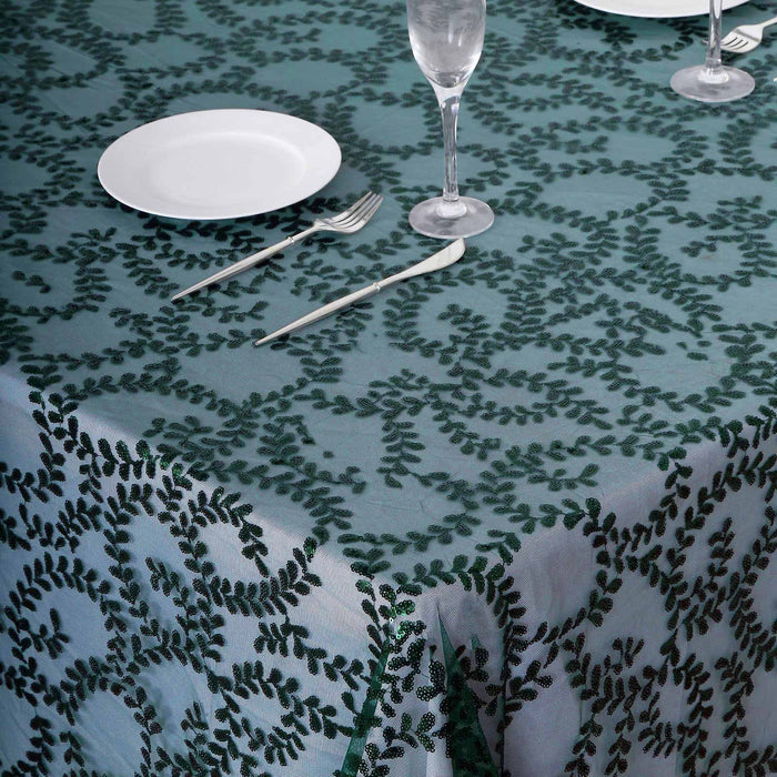 Elegant green leaf pattern tablecloth with plates and cutlery set for dining.